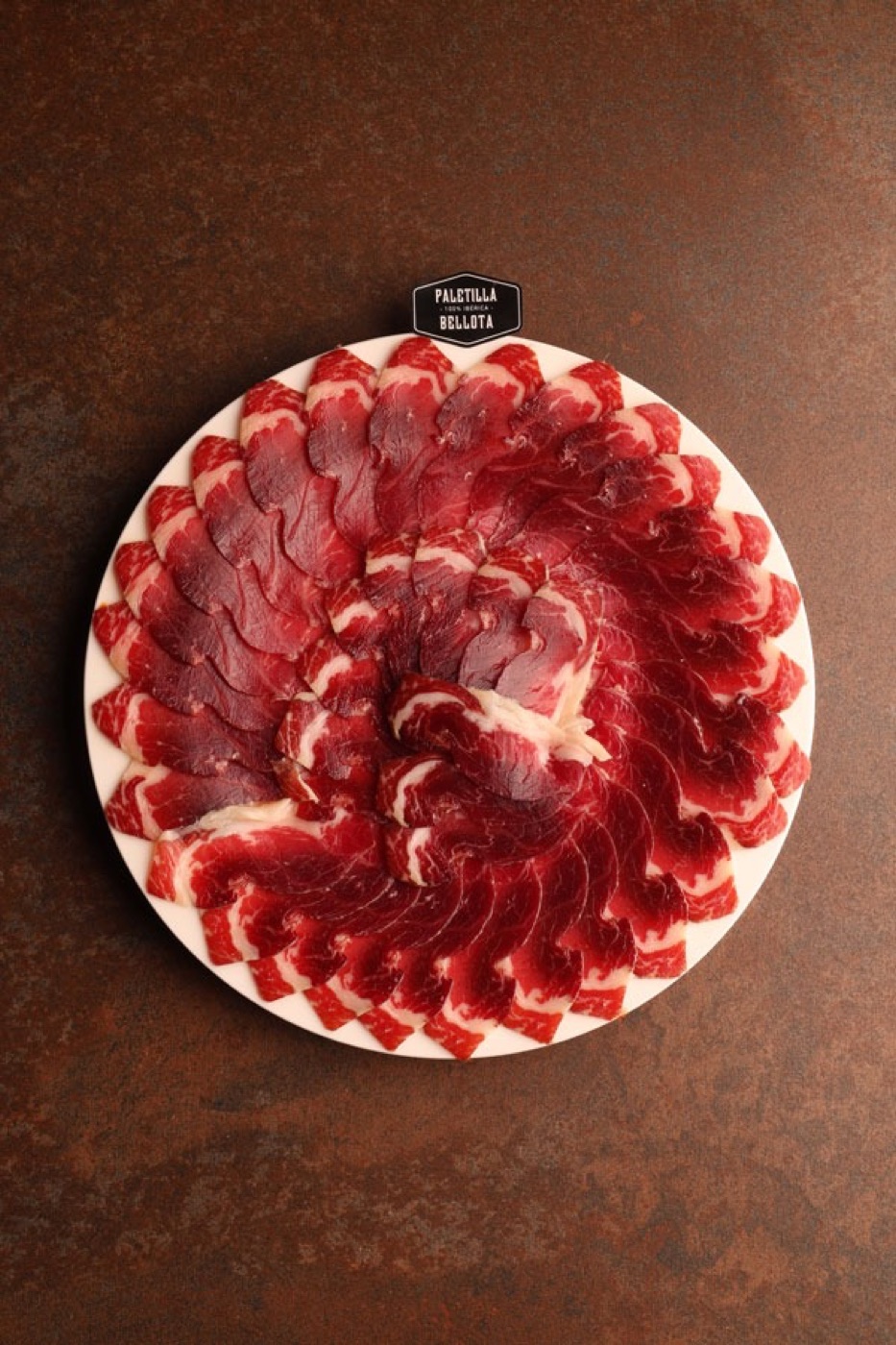 Lonchas de ibérico de bellota extendidas sobre plato blanco